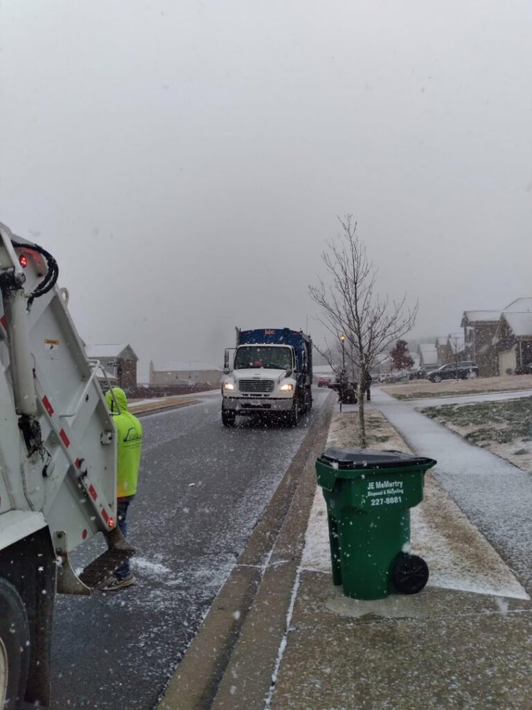 A J.E. McMurtry Disposal & Recycling garbage truck and a worker on a snowy residential street in Nashville, TN.