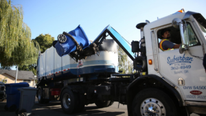 A Suburban Garbage Service truck collecting a blue residential waste bin in Salem, OR.