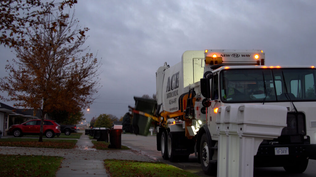 An Ace Sanitation Service Inc. garbage truck collecting residential waste with an automated arm in Columbus, NE.