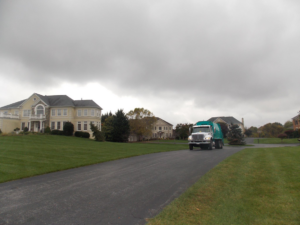 An Elegant Recycling & Refuse Services Inc. garbage truck collecting waste on a residential street in Spencerville, MD.