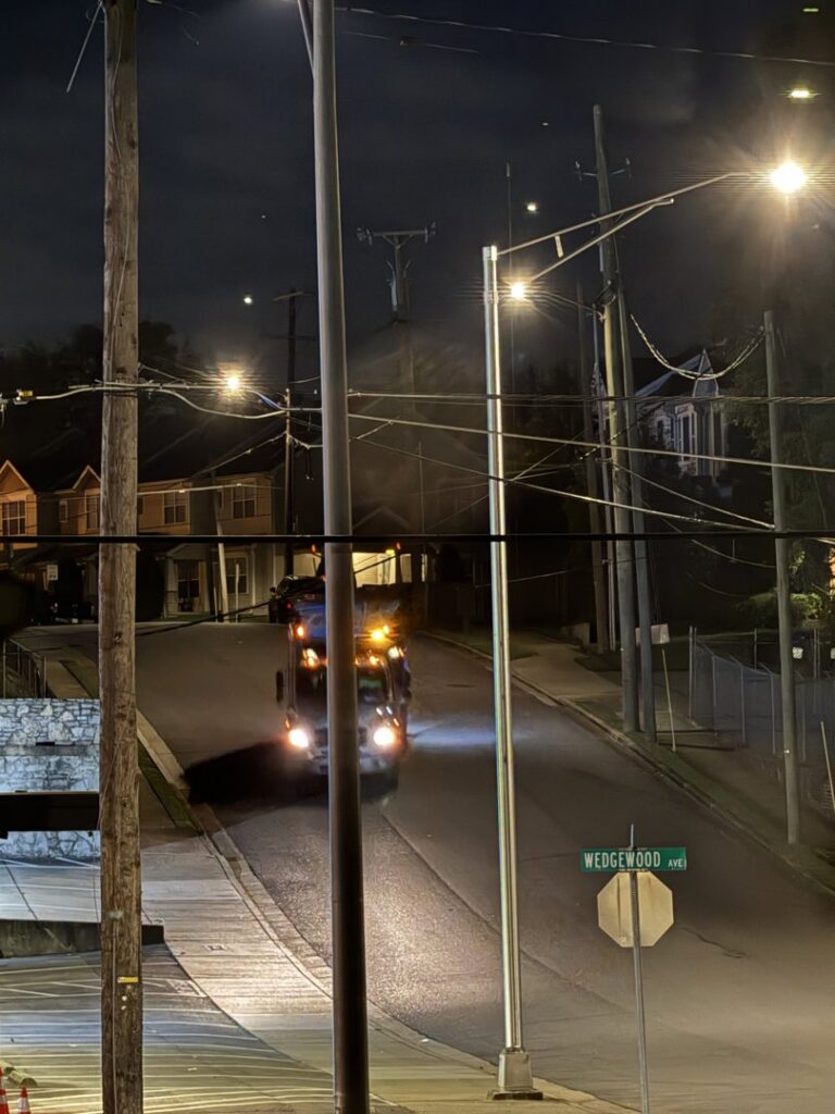 A J.E. McMurtry Disposal & Recycling garbage truck driving on its collection route at night in Nashville, TN.