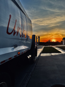 The side of a Uribe Refuse Services garbage truck on a street at sunset in Lincoln, NE.
