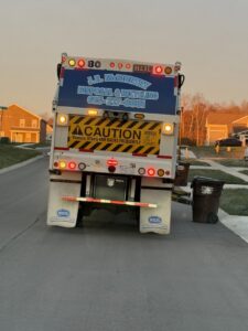 A J.E. McMurtry Disposal & Recycling garbage truck positioned next to a trash bin for collection in Nashville, TN.
