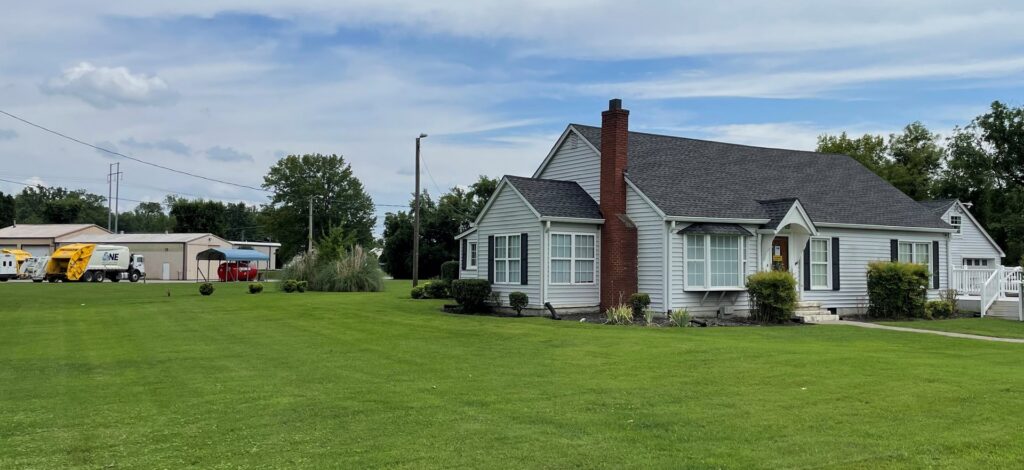 Two One Waste Solutions garbage trucks visible in the background of a residential area in Murfreesboro, TN, providing junk removal.