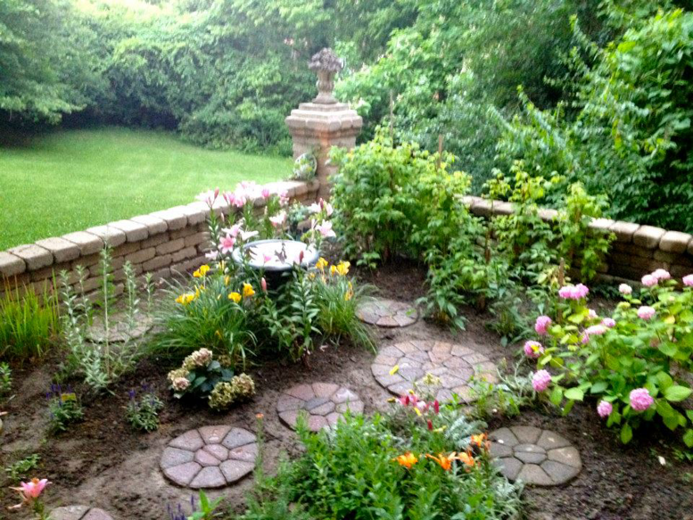A garden bed with a brick retaining wall and circular stepping stones by Massa Paving Company in Cincinnati, OH.