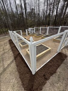 A newly installed fenced garden area with raised beds and mulch, completed by Ed Hauls It All in Raleigh, NC.