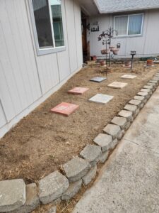 A garden bed being prepared with stepping stones and a retaining wall, a service offered by Battleship Property Maintenance in Lewiston, ID.