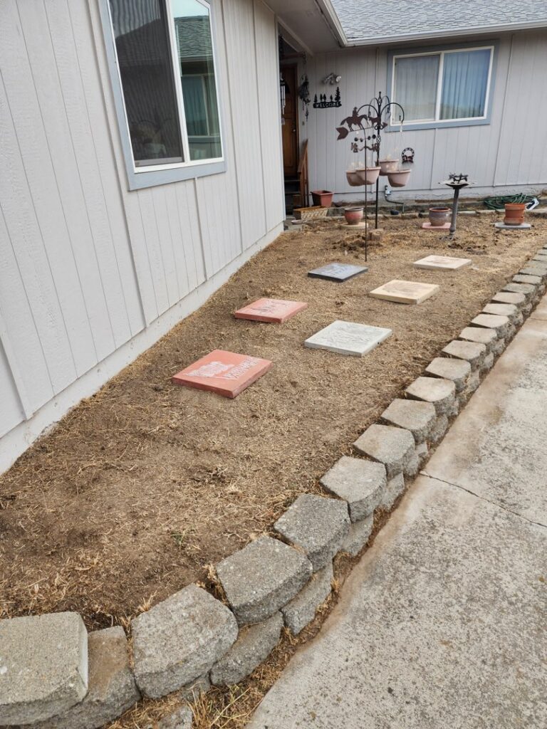 A garden bed being prepared with stepping stones and a retaining wall, a service offered by Battleship Property Maintenance in Lewiston, ID.