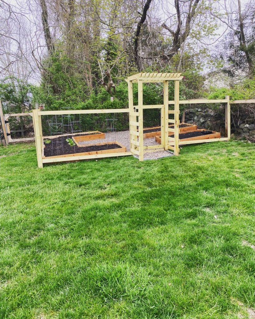 A garden area featuring newly built raised beds and a wooden arbor by Woodbine Repair & Remodeling in Jamestown, RI.