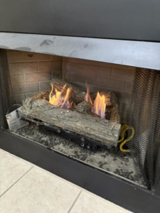 A gas fireplace with burning logs, indicating installation or repair service by Express Handyman Pros, LLC in Fort Smith, AR