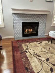 A gas fireplace with a decorative tile surround and white mantel installed by Infinite Fire Features in Colorado Springs, CO.