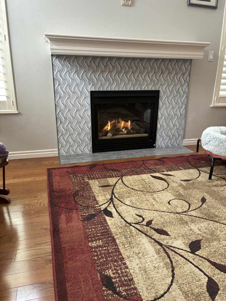 A gas fireplace with a decorative tile surround and white mantel installed by Infinite Fire Features in Colorado Springs, CO.