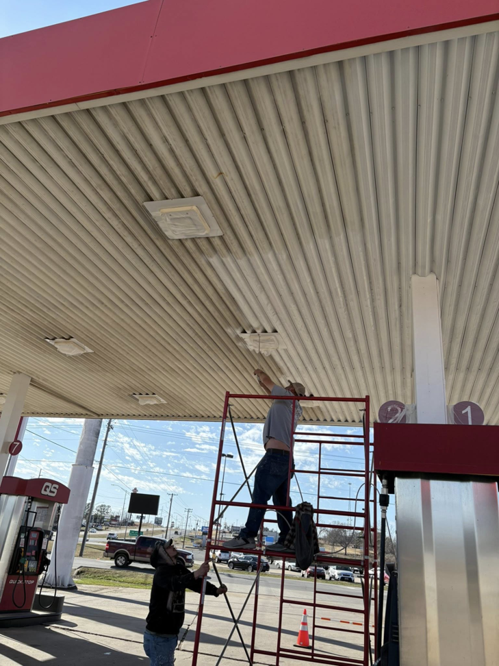 A handyman on scaffolding repairing lights under a gas station canopy for Express Handyman Pros, LLC in Fort Smith, AR