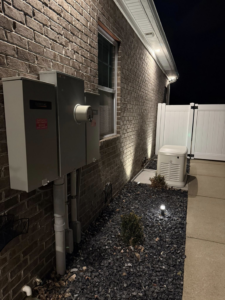 A Generac whole-house generator installed at night with exterior lighting by Morris Electrical Service in Hopkinsville, KY.