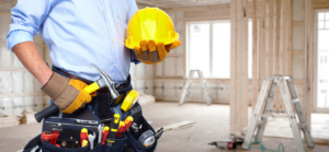 A general contractor wearing a tool belt and holding a hard hat in a construction site by Los Angeles Handyman Pro in Los Angeles, CA.