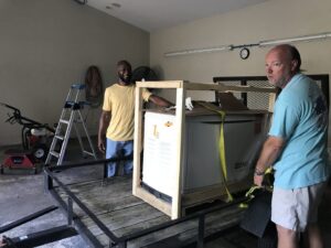 Two workers delivering a crated Generac generator for installation by Carolina Custom Electric in Mount Pleasant, SC.