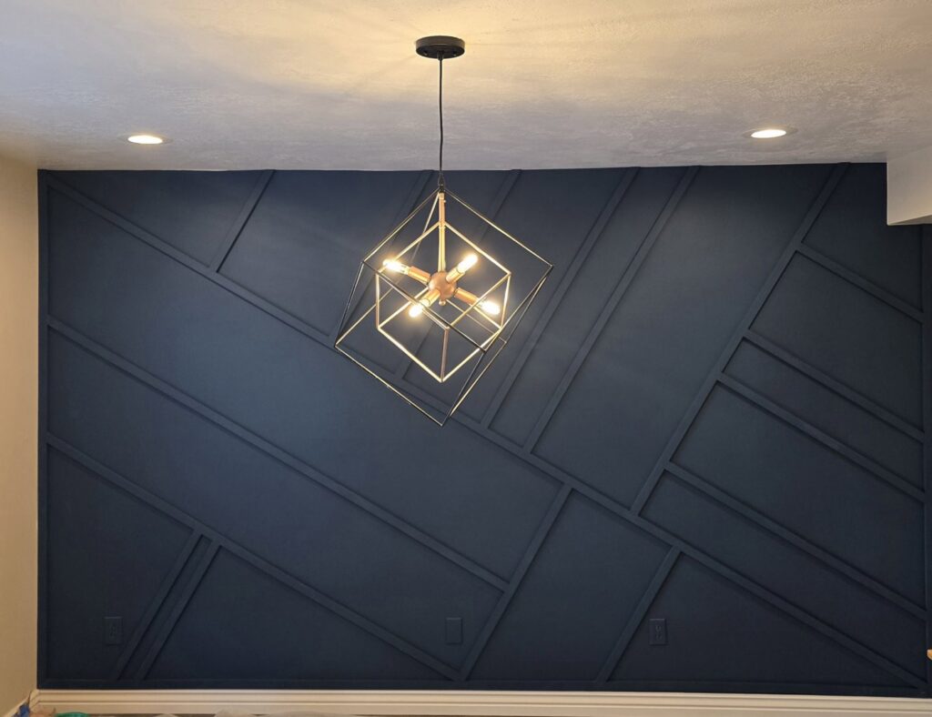 A dark blue geometric accent wall with a modern light fixture installed by Halpin Hands in Williams, OR.