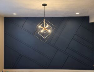 A dark blue geometric accent wall with a modern light fixture installed by Halpin Hands in Williams, OR.