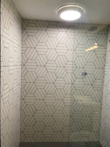 An interior view of a shower with striking geometric pattern wall tiles by CSR Tile Construction LLC in Minneapolis, MN.