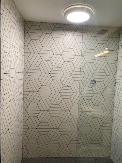 An interior view of a shower with striking geometric pattern wall tiles by CSR Tile Construction LLC in Minneapolis, MN.