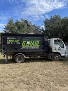 A G.I. HAUL Austin, TX junk removal truck loaded with construction debris and large items on a grassy lot.