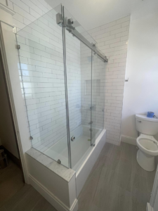 A modern glass sliding shower door enclosure installed over a bathtub by Anderkin Remodeling in Cincinnati, OH