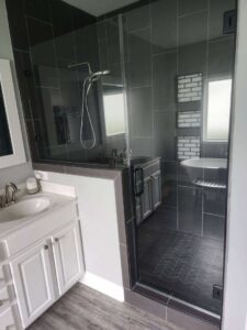 A modern bathroom remodel featuring a large glass shower enclosure and white vanity by Donaldson & Company Construction in Charlotte, NC.