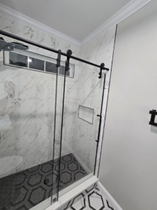 Newly installed glass shower enclosure with modern tile work by Hollis Construction in Nashville, TN.
