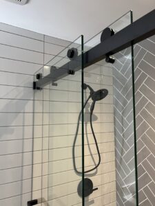 Close-up of a new glass shower enclosure installation by Jocia Construction Services in Gilbert, AZ.