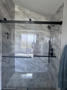 A modern glass shower with marble-look wall tiles and hexagonal floor tiles by A&R Home Improvements in El Paso, TX