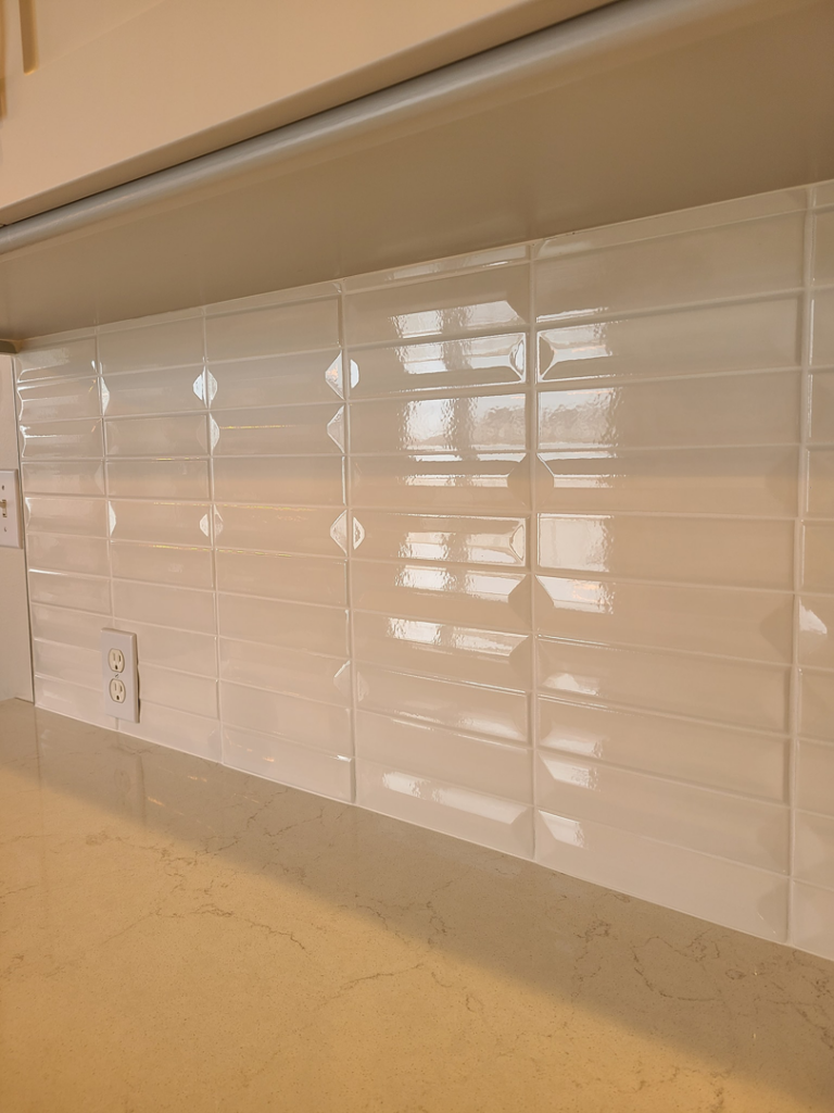 A modern kitchen backsplash featuring glossy white beveled subway tiles installed by Bryan's Home Services in Fargo, ND.