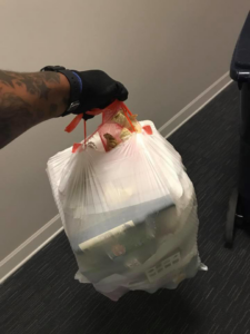 A gloved hand holding a full trash bag, demonstrating the junk removal service by Elite Valet Trash in Apex, NC.