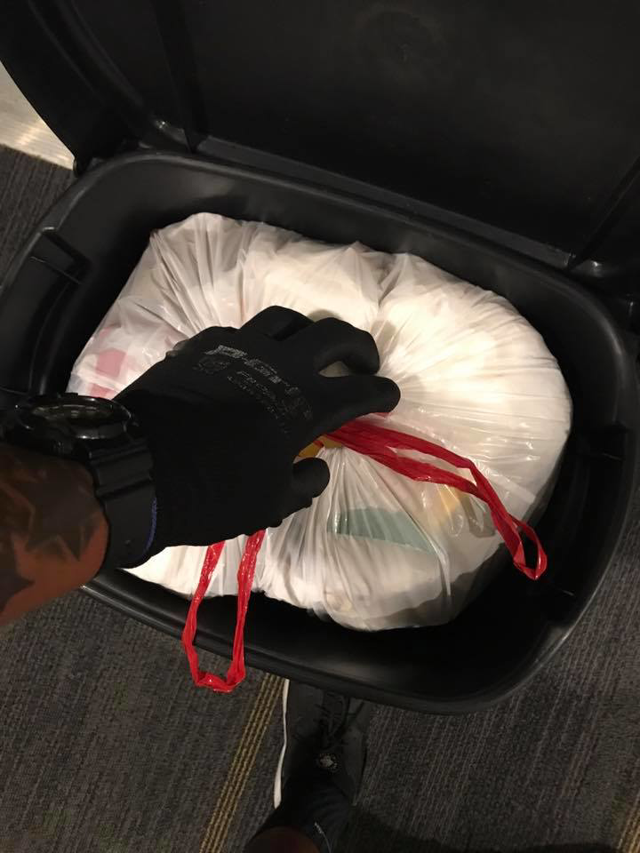 A gloved hand tying a full trash bag inside a bin, part of the service provided by Elite Valet Trash in Apex, NC.