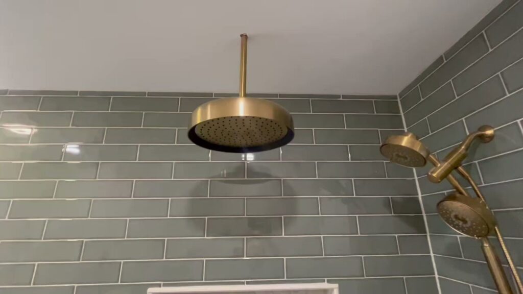A newly installed gold rain shower head and fixtures in a tiled bathroom by Stanley Contracting in Whiting, NJ