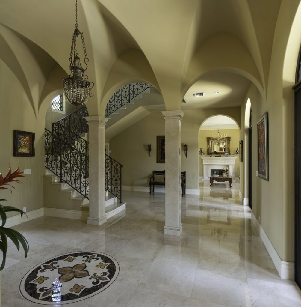 A grand home entryway featuring arched ceilings, marble floors, and a wrought iron staircase by Madison Construction Group, Inc. in Miami, FL