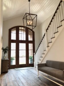 A grand entryway with a tall arched door and elegant staircase, completed by Creasey Construction of Illinois, Inc. in Springfield, IL
