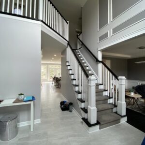 A grand foyer featuring a newly renovated staircase with white balusters and grey walls, completed by Bob Build's WNY in Buffalo, NY.