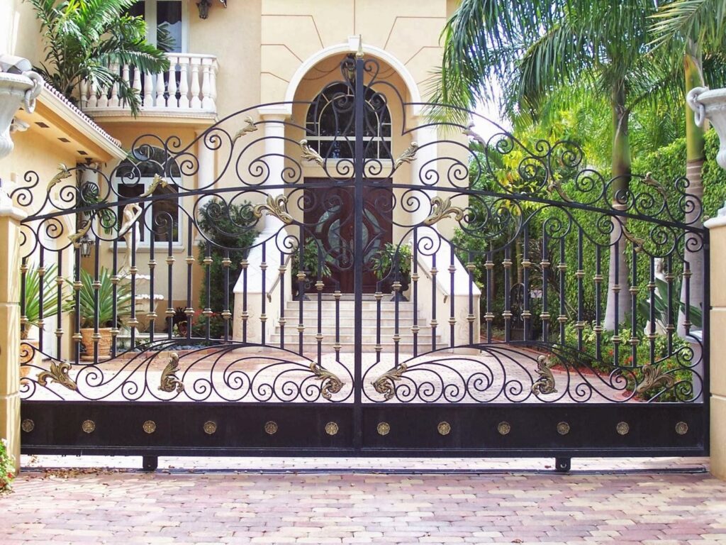 Grand ornate black and gold wrought iron driveway gate installed by Xclusive Fence And Rails Inc. in Miami, FL.