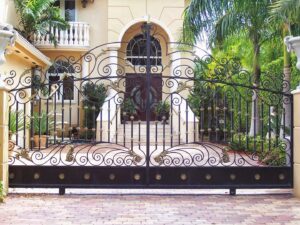 Grand ornate black and gold wrought iron driveway gate installed by Xclusive Fence And Rails Inc. in Miami, FL.