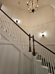 A grand staircase renovation featuring dark wood handrails, white balusters, and wainscoting by Amazing Spaces 21 in Orlando, FL