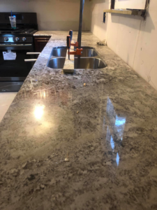 Granite countertop installation in progress, showing clamps securing the new countertop over a double sink by Fine Design Marble And Granite in Springfield, MA.