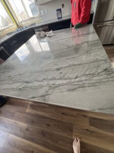 A worker installing a large granite countertop on a kitchen island for Victor's Granite Counter-Tops in Millcreek, UT.