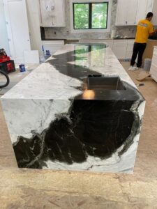 A large granite kitchen island being installed by a worker from J and R Granite Industry in Columbus, OH.