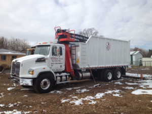 A white grapple truck with the Aesthetic Tree Service logo and contact information in Denver, CO.