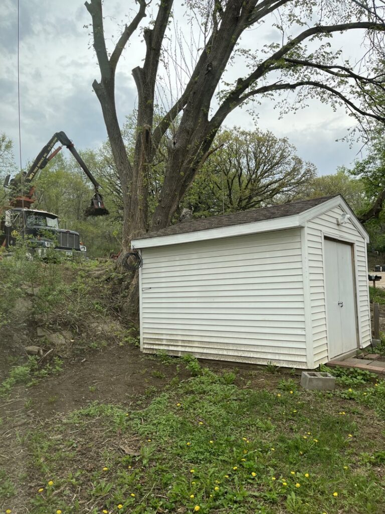 A grapple truck and pile of tree debris at a job site, showcasing the cleanup services of Jeff's Tree Service in Sioux City, IA.