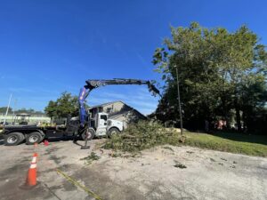 A blue grapple truck loading tree debris after a service by Royal Oak Tree Services in Jacksonville, FL.