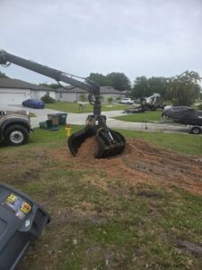 A grapple truck attachment removing a pile of wood chips and debris for Tim's Tree Service in Cape Coral, FL