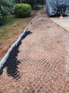 A gravel path with a black drainage grid being installed by Drip Dry Drainage in Cramerton, NC.