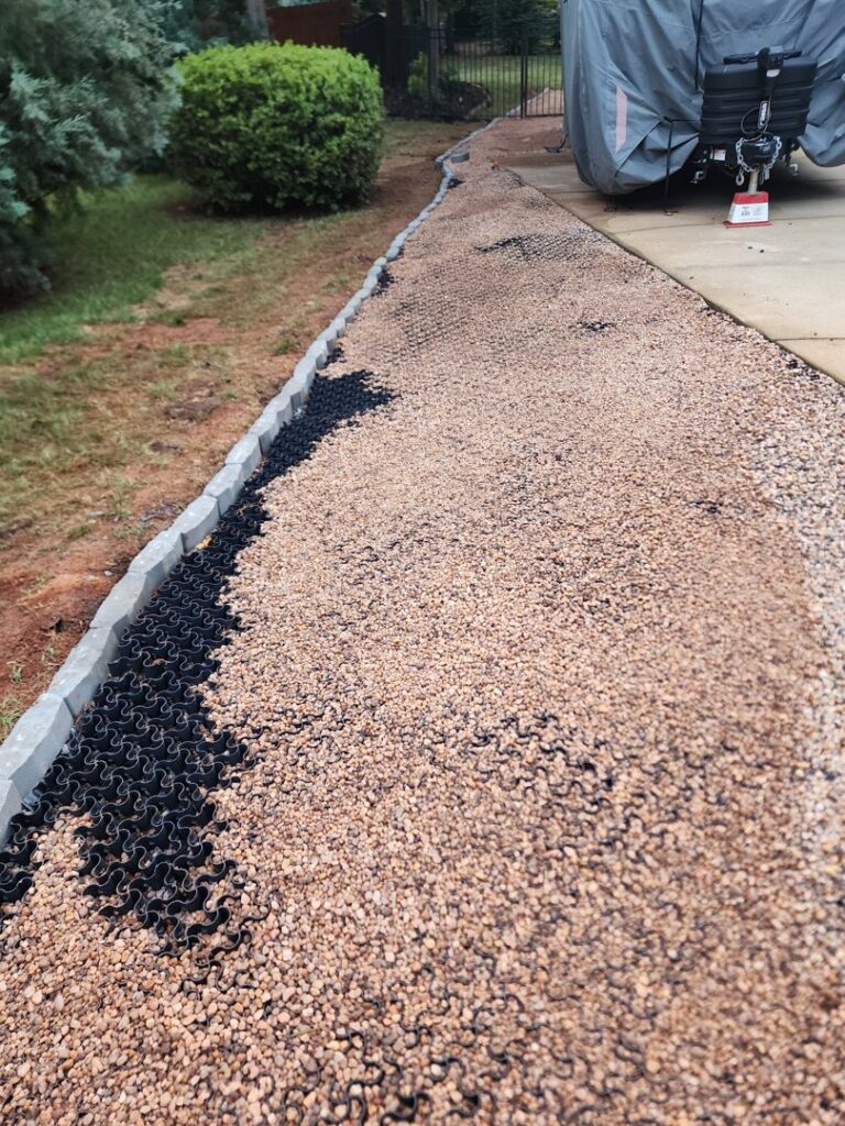 A gravel path with a black drainage grid being installed by Drip Dry Drainage in Cramerton, NC.