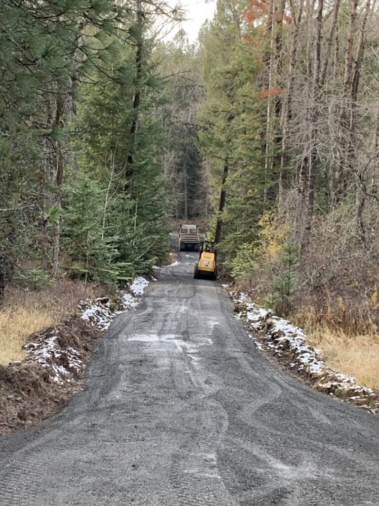 A gravel road under construction or maintenance, with excavation equipment in the distance, by Aspen Excavation in Spokane, WA.